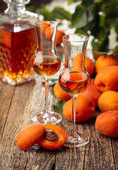 Apricot liquor and fresh apricots on a old wooden table.