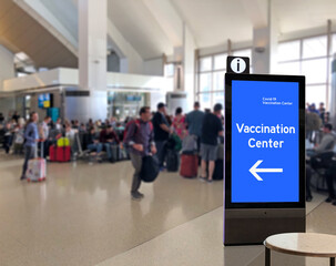 Crowd of people at airport terminal with Corona Virus Vaccination kiosk or info display Covid19 info kiosk, signage or signboard 