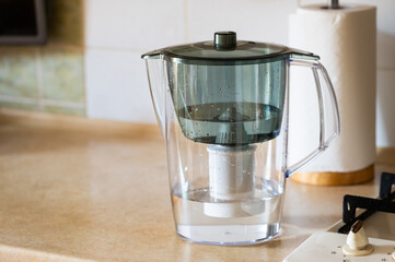 Water filter jug on kitchen table. Clean water concept. Filtration water