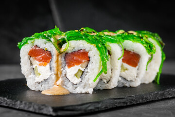 appetizing sushi roll with philadelphia cheese cucumber salmon and chuka on a black stone plate