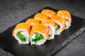 appetizing sushi roll philadelphia with salmon cucumber and chuka on a black stone plate