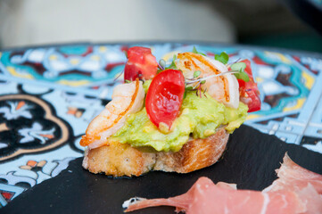 tapas crunchy bread with shrimp, avocado, tomato and wheat germ, spanish food