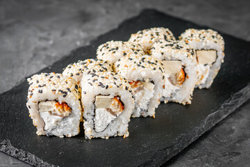 appetizing sushi roll california with eel tofu sesame and unagi cheese on a black stone plate