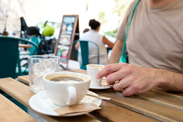Man drinking a coffee sat on a table outdoors