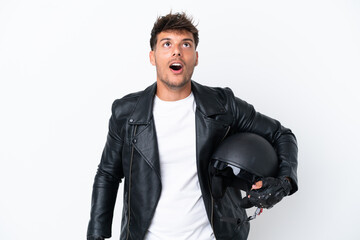 Young caucasian man with a motorcycle helmet isolated on white background looking up and with surprised expression