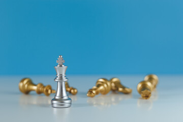 Chess game silver king standing confront the gold team. blue background, business leader strategy concept.