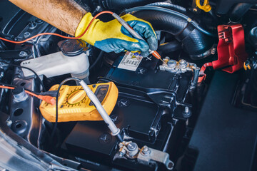 Technician checking DC voltage stable of the car battery with digital multimeter probe