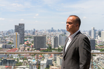 Fototapeta na wymiar Profile view portrait of Indian businessman in city at Bangkok, Thailand
