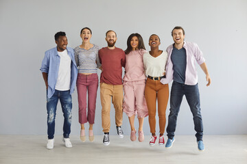 Diverse group of happy young people jumping in studio. Bunch of cheerful positive excited international multicultural mixed race college students in casual clothes jumping together and laughing - Powered by Adobe