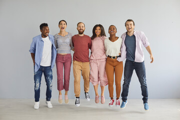 Diverse group of happy young people jumping in studio. Bunch of cheerful positive excited...