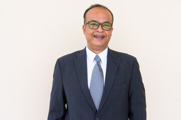 Portrait of Indian businessman smiling against plain wall outdoors