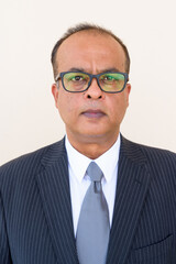 Portrait of Indian businessman wearing eyeglasses against plain wall outdoors