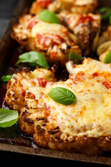 Baked Cauliflower steak with marinara sauce and cheese on rustic tray. Healthy vegetarian food