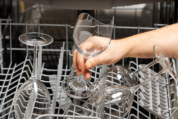 Broken wine glass in the dishwasher after washing. hand holds a broken glass in front of an open dishwasher. glasses breaking in the Dishwasher - Powered by Adobe