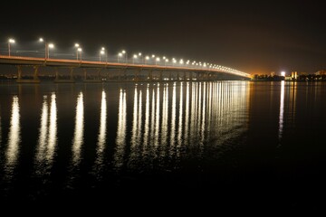 Fototapeta na wymiar Reflection of bright lanterns in the Dnieper river under the bridge