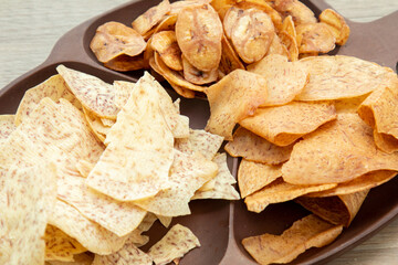 Asian sweet and salty snacks, tasty mixed cornflakes, fried banana and fried taro, nut, grape, and caramel on wooden background natural light. sweet snacks with a cup of tea and copy space