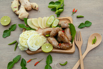 Asian yummy appetizer for meal or snack with natural light, process food product from pork, natural fermented sour pork wrap by banana leaves decorate by vegetable, chili, ginger bergamot, and lemon