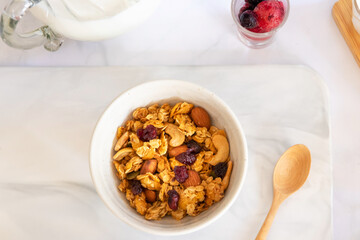 Granola with milk and berries in a white bowl; top view on white table. Healthy breakfast concept.