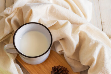 Milk in vintage mug on wooden table; winter day.
