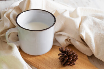 Milk in vintage mug on wooden table; winter day.
