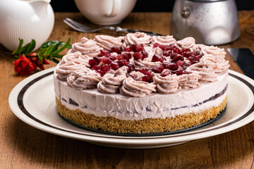 Homemade pomegranate cheesecake garnished with cream and pomegranate seed.