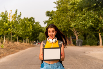 Young caucasian girl showing blank board in the park