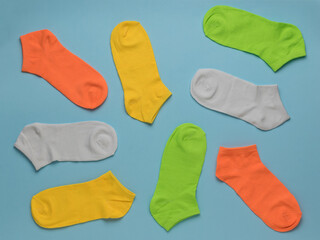 Multi-colored short sports summer socks scattered on a blue background.