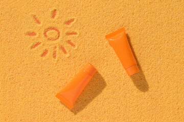 A painted sun on the sand and two tubes of sunscreen.