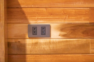 The bed head power socket is mounted on the wooden wall in the room