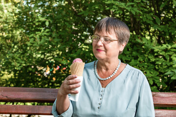 Grandma is eating ice cream in a summer park.