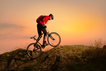 Fototapeta na wymiar Cyclist in Red Riding Bike on the Spring Rocky Trail at Sunset. Extreme Sport and Enduro Biking Concept.