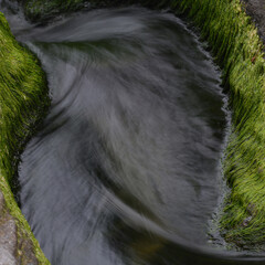 A stream flowing between slate boulders at Trebarwith Strand Cornwall