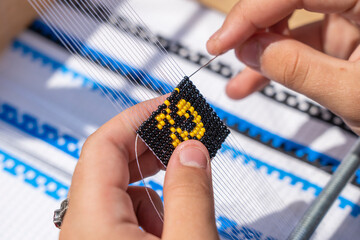Young girl makes a beaded bracelet with her hands, Ukraine, close up