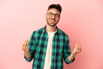 Fototapeta premium Young caucasian man isolated on pink background making money gesture