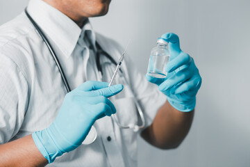 A doctor or scientist in a medical research laboratory holding a syringe containing a liquid vaccine analyzes an antibody sample to boost the patient's immunity.
