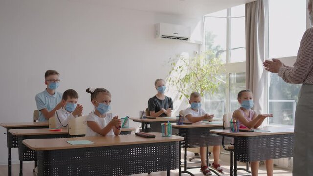 The teacher shows the children the rules of personal hygiene, how to wash their hands, how to treat their hands with antiseptic. how to use a sanitizer. At school in protective masks