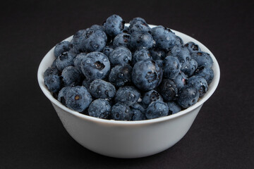 Fresh Blueberries in a bowl on dark background, Juicy wild forest berries, bilberries. Healthy eating or nutrition.