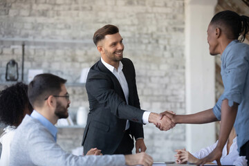 Smiling diverse multiethnic businessmen shake hands close deal or make agreement at meeting in office. Happy multiracial businesspeople handshake get acquainted greet at briefing. Teamwork concept.