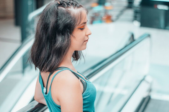 Chica joven con tristeza mirando en las escaleras mecanicas de un centro comercial