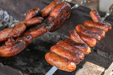 Sausages and meat on a wooden skewers on the grill, close-up.