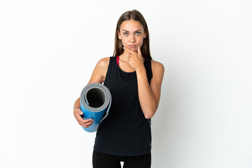 Fototapeta premium Sport woman going to yoga classes while holding a mat over isolated white background thinking
