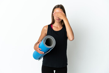 Sport woman going to yoga classes while holding a mat over isolated white background covering eyes by hands. Do not want to see something