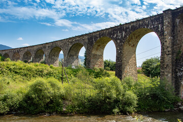 Fototapeta na wymiar Arched viaduct in the mountains with a river