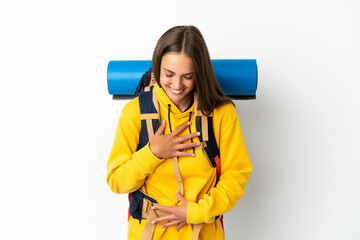 Young mountaineer woman with a big backpack over isolated white background smiling a lot