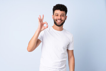 Young Moroccan man isolated on blue background showing ok sign with fingers