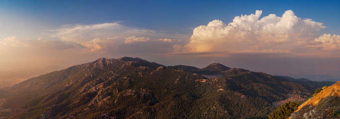 Sunset light over hills around of the Babadag mountain, panoramic view. Wide landscape with mountains and beautiful clouds on top viewpoint in Fethiye.