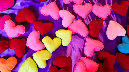 Multicolored and bright plush hearts on a purple bed background. Valentine's day or love concept.