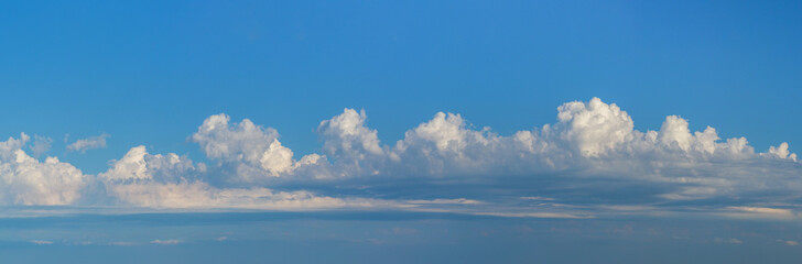 Panorama of a cloudy sky with cumulus fluffy clouds. Wide horizontal sky landscape and beautiful skyline for sky background on weather banner.