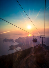 Panoramic view from the Fethie funicular cable car. Skywalk Babadag at sunset with sunlight beams on skyline. Top view on islands next to the coast of Oludeniz resort in Mugla province, Turkey.
