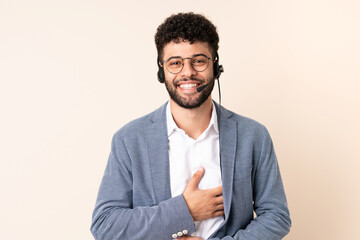 Telemarketer Moroccan man working with a headset isolated on beige background smiling a lot
